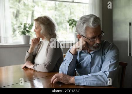 Turbato marito anziano moglie sedersi al tavolo separatamente evitare di parlare Foto Stock