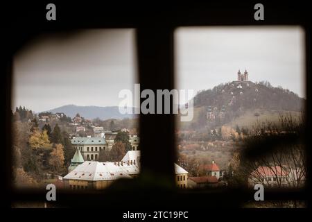 Vista panoramica da dietro la finestra sulla città di Banská Štiavnica, nella Slovacchia centrale, con il suo simbolo iconico: Il Calvario di Banská Štiavnica Foto Stock