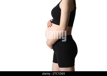 Donna incinta che sporge l'addome e lo copre con le mani (isolata su sfondo bianco) Foto Stock