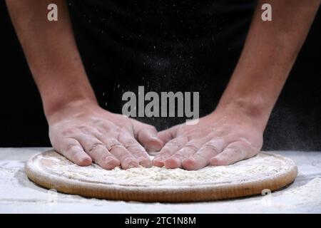 Gli chef mani e farina su uno sfondo scuro, primo piano. Mani nella farina Foto Stock