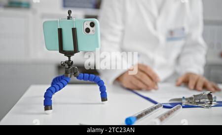 Uomo dai capelli grigi di mezza età, uno scienziato devoto in laboratorio, coinvolto nella sua ricerca, scrive meticolosamente sugli appunti utilizzando il suo smartphone Foto Stock