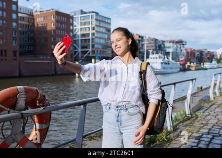 Giovane studentessa turista adolescente che scatta foto selfie su smartphone nella città portuale europea Foto Stock