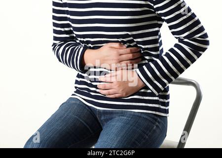 giovane donna che soffre di mal di stomaco, primo piano. avvelenamento da cibo, crampi, isolati Foto Stock