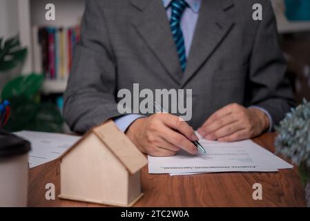 Persona d'affari che scrive il diritto contrattuale e lavoro di carta per il commercio e la finanza, scriva il documento, i moduli completi di domanda di lavoro, il bene immobile di contratto e. Foto Stock
