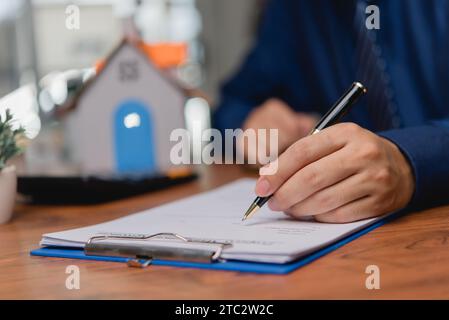 Persona d'affari che scrive il diritto contrattuale e lavoro di carta per il commercio e la finanza, scriva il documento, i moduli completi di domanda di lavoro, il bene immobile di contratto e. Foto Stock