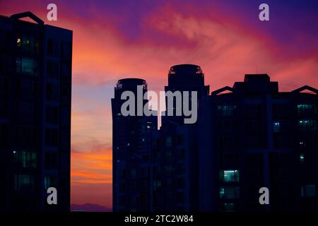 Il cielo di Ulsan al tramonto, con le silhouette scure degli appartamenti e il cielo vibrante. Foto Stock