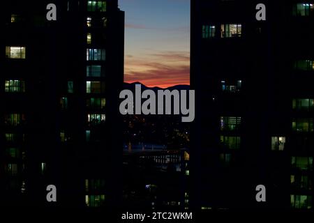 Lo skyline di Ulsan al tramonto, con le sue oscure sagome di appartamenti, il cielo vibrante, il tranquillo fiume Taehwa e l'iconico ponte Taehwa. Foto Stock