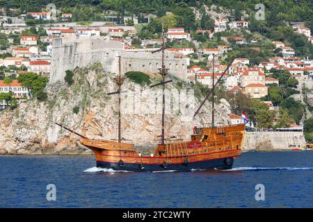 Tradizionale nave Karaka che naviga oltre le mura fortificate della fortezza di Dubrovnik (Croazia), replica di galeoni nel Mare Adriatico, patrimonio culturale croato Foto Stock