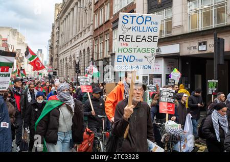 Londra / Regno Unito - 9 dicembre 2023: Un anziano manifestante pro-palestinese tiene un cartello con la scritta "ferma l'uccisione, rilascia gli ostaggi, metti fine all'occupazione" Foto Stock