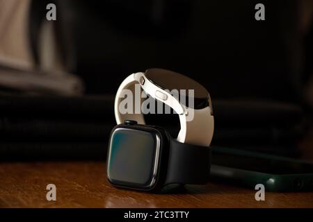 Dnipro, Ucraina - 10 dicembre 2023: Gli smart Watch bianchi Samsung Galaxy Active e Apple Watch Series 8 si trovano sul tavolo a casa, due smart Watch Foto Stock