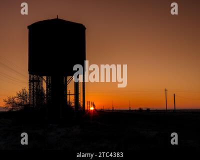 Vecchio silo d'acqua lungo i binari del treno all'alba Foto Stock