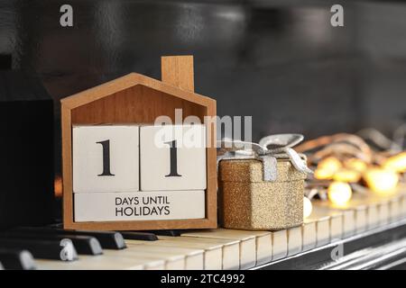 Calendario con testo 11 GIORNI FINO ALLE FESTIVITÀ e decorazioni natalizie sulle chiavi del pianoforte Foto Stock