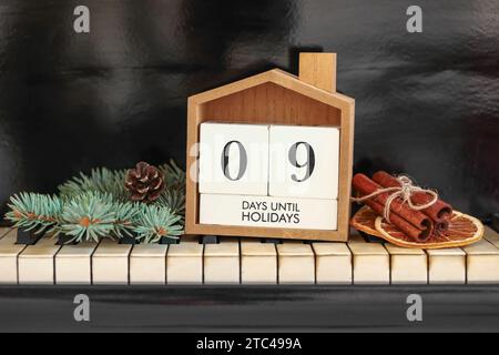 Calendario con testo 9 GIORNI FINO ALLE FESTIVITÀ e decorazioni natalizie sulle chiavi del pianoforte Foto Stock