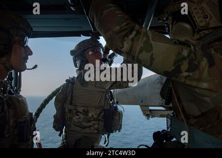 I tecnici di smaltimento degli esplosivi della Marina degli Stati Uniti si preparano a scendere una corda veloce da un elicottero MH-60S Sea Hawk, attaccato al "Dusty Dogs" dell'Helicopter Sea Combat Squadron (HSC) 7, mentre conducono un addestramento sulla tecnica di sospensione della corda dell'elicottero a bordo del cacciatorpediniere USS Gravely (DDG 107) nel Golfo Arabico, 5 dicembre 2023. Il Dwight D. Eisenhower Carrier Strike Group è schierato nell'area operativa della 5th Fleet degli Stati Uniti per sostenere la sicurezza marittima e la stabilità nella regione del Medio Oriente. (Foto della Marina degli Stati Uniti di Mass Communication Specialist 2nd Class Kalvin Kes) Foto Stock