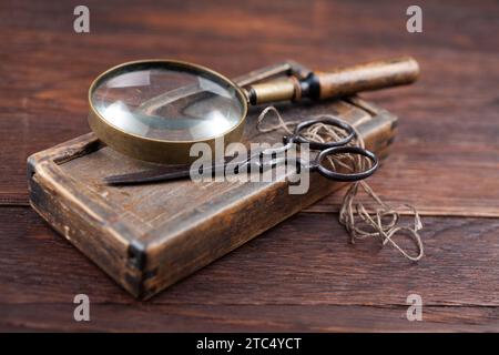 Accessori antichi scatola in legno, vecchie forbici retrò vintage e lente di ingrandimento. Sfondo nostalgico retrò sentimentale. Foto Stock