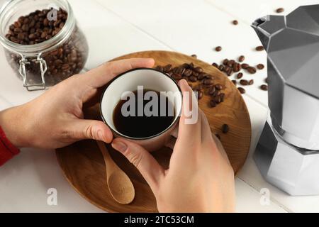 Uomo con una tazza di caffè aromatico, primo piano. Moka e fagioli su un tavolo di legno bianco Foto Stock