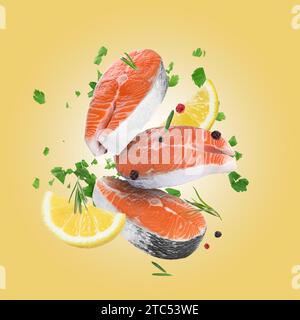 Bistecche di salmone fresco, spezie e fette di limone che cadono su sfondo dorato Foto Stock