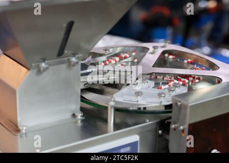 Capsule per pillole e macchina automatica per il riempimento di bottiglie per pillole. Linea di produzione farmaceutica industriale. Messa a fuoco selettiva. Foto Stock