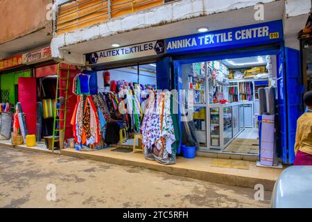 Un commerciante sta aspettando degli acquirenti fuori dai suoi negozi tessili in via Biashara il 19 ottobre 2023 a Nairobi, Kenya. Nelle ultime settimane, ho documentato il viaggio di Afrowemaís verso il Just Fashion Day all'evento Eco Fashion Week Kenya che si è svolto il 23 novembre 2023. Afrowema (un marchio sociale di moda etico e sostenibile nato a Kibera, Kenya, il più grande slum dell'Africa, Afrowema contribuisce all'empowerment degli artigiani in questa comunità e crea nuove opportunità di lavoro utilizzando materiali locali nuovi e usati) è stata fondata da Tatiana. Poco prima dell'evento, Tatiana accompa Foto Stock