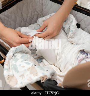 Una madre mette i calzini sul suo neonato, il bambino è sdraiato in un passeggino. Foto Stock