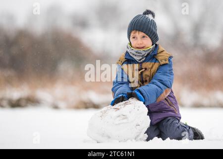 Il bambino di sei anni fa fa il pupazzo di neve Foto Stock