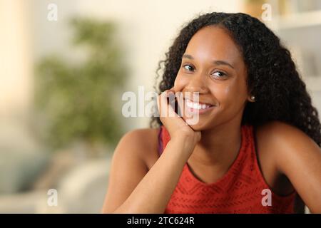 Bella donna nera che sorride alla telecamera che posa a casa Foto Stock