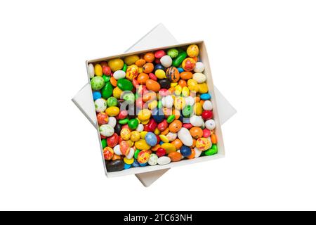 Set di caramelle dolci diverse in una scatola di carta con un nastro di raso su uno sfondo colorato. Concetto di vacanza. Foto Stock