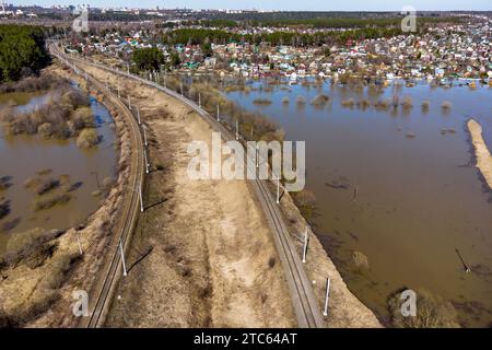 Vista aerea di una ferrovia che attraversa una campagna allagata durante le inondazioni primaverili Foto Stock