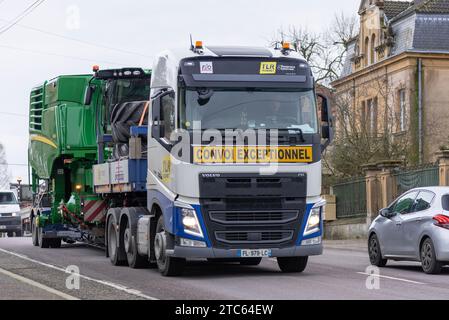 Delme, Francia - autocarro bianco per trasporto pesante Volvo FH 500 con attrezzatura da raccolta John Deere su strada. Foto Stock