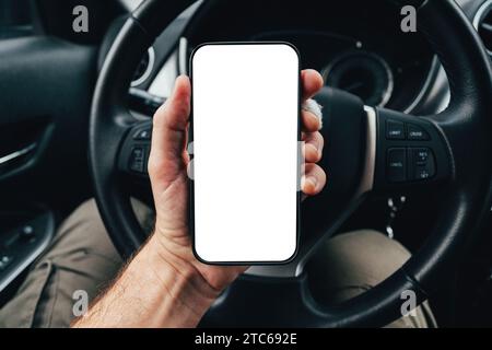 Modello app conducente con schermo dello smartphone vuoto sul volante, uomo che tiene il telefono cellulare in auto, messa a fuoco selettiva Foto Stock