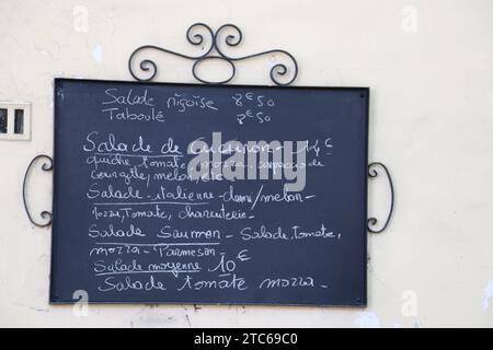 Un primo piano di un menu visualizzato su una lavagna a muro all'esterno di un accogliente caffè Foto Stock