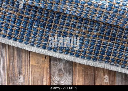 Tappeto in denim geometrico intrecciato a mano su pavimento in legno. Foto Stock