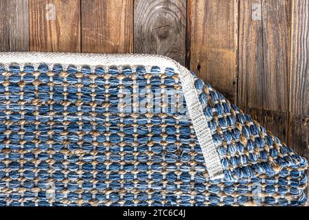 Tappeto in denim geometrico intrecciato a mano su pavimento in legno. Foto Stock