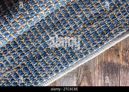 Tappeto in denim geometrico intrecciato a mano su pavimento in legno. Foto Stock