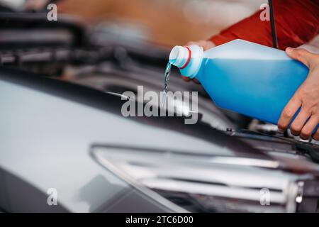 Versare il liquido lavavetri invernale nel serbatoio dell'auto durante l'inverno, proteggendolo dal congelamento. Foto Stock