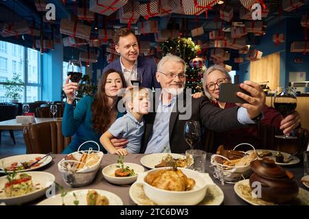 La famiglia si diverte mentre si scatta un selfie al tavolo da pranzo il giorno del Ringraziamento Foto Stock