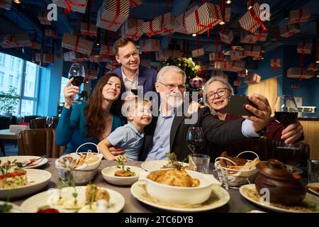 Famiglia che scatta selfie videochiama sullo smartphone mentre festeggia il Natale Foto Stock