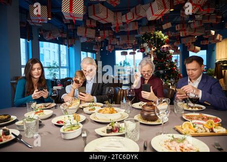 Famiglia che usa i propri gadget durante le celebrazioni natalizie Foto Stock