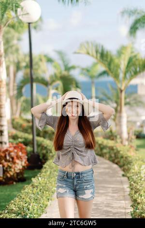 Una giovane donna in abiti estivi passeggia tra le palme dominicane Foto Stock