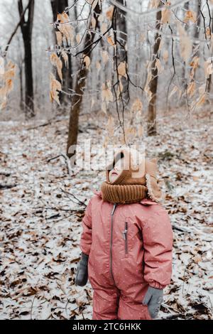 Bambino in muta da neve che guarda i ghiaccioli sugli alberi Foto Stock