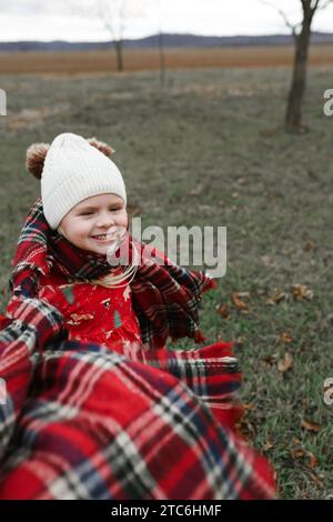 Giovane ragazza nei campi invernali con sciarpa che soffia nel vento Foto Stock