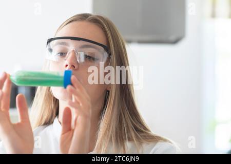 giovane scienziato con occhiali da laboratorio e con tubo verde Foto Stock