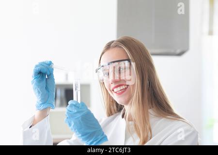 giovane scienziata femmina con capelli lunghi e occhiali da laboratorio che lavorano Foto Stock