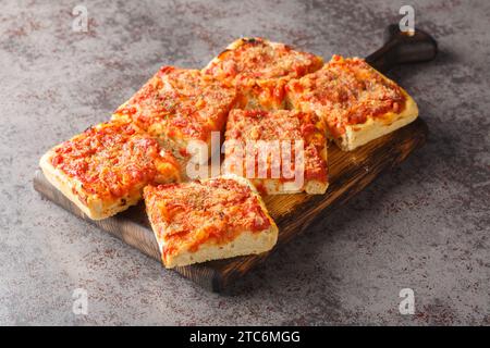 Sfincione tipica focaccia al forno molto morbida e condita con pomodoro, cipolla, acciughe, formaggio, origano e pangrattato primo piano sul boa di legno Foto Stock