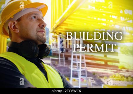 Ritratto di giovane è un ingegnere che indossa il casco sorride con soddisfazione in cantiere con il cartello "permesso di costruzione". Foto Stock