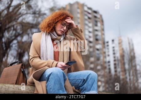 Ritratto naturale di una donna zenzero caucasica con lenticelle e capelli ricci. È depressa. Foto Stock
