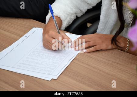 giovane donna che firma un documento su carta con una semplice penna. Foto Stock