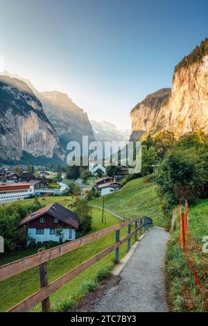 Vista mozzafiato della valle di Lauterbrunnen con il villaggio rustico, la famosa chiesa e le cascate di Staubbach durante la fine dell'estate al mattino al Canton Berna Foto Stock