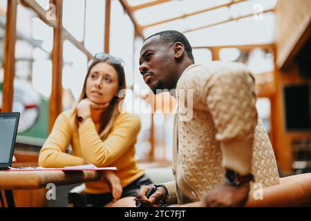 Il team di startup multiculturale si occupa di strategie per la crescita aziendale, la redditività e la garanzia di finanziamenti da parte di investitori angelici in una riunione di bar alla moda. Foto Stock