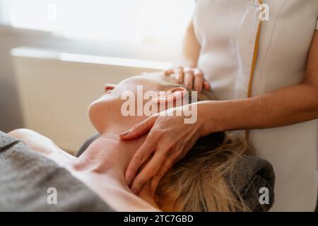 Primo piano di un terapista che fa un massaggio al collo e alle spalle a una donna sdraiata. Salone di bellezza immagine concept Hotel benessere Foto Stock